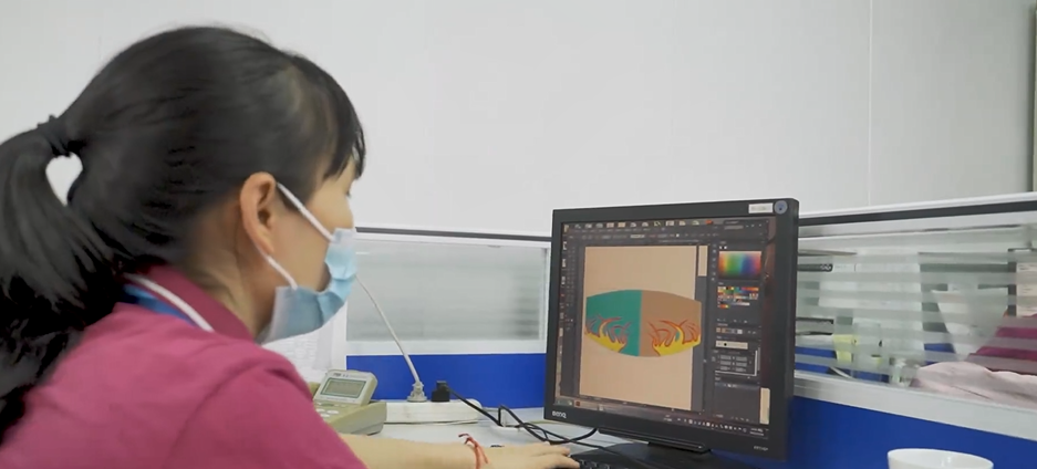 Textile designer working at computer with fabric samples and design tools in modern office environment